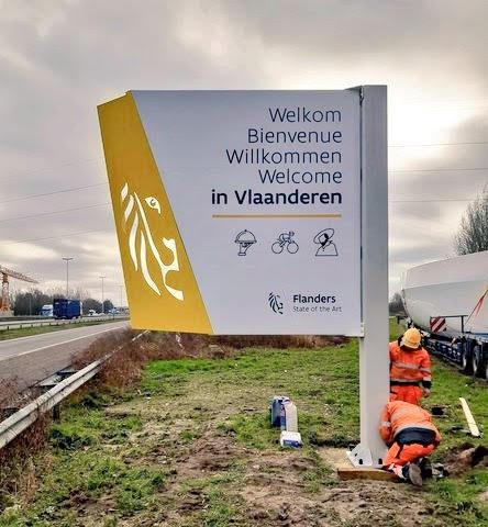 Arbeiders plaatsen een verwelkomingsbord naast de snelweg.