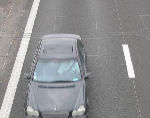 Auto rijdt over meetlussen in het wegdek.