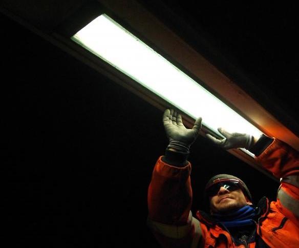 Technicus vervangt lamp in tunnel.
